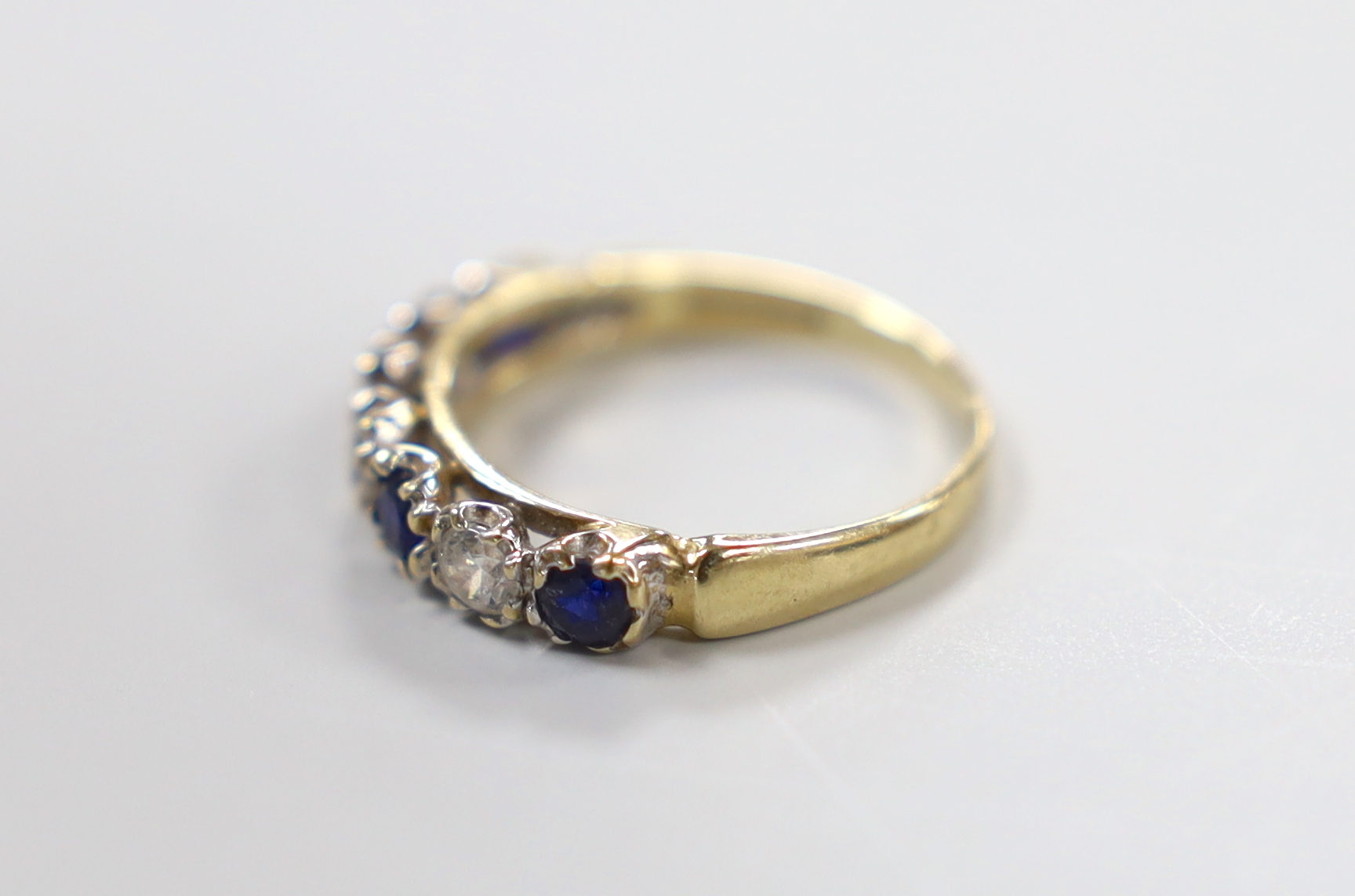 A modern 14ct gold and two colour sapphire? set half hoop ring, size K/L, gross weight 2.3 grams.